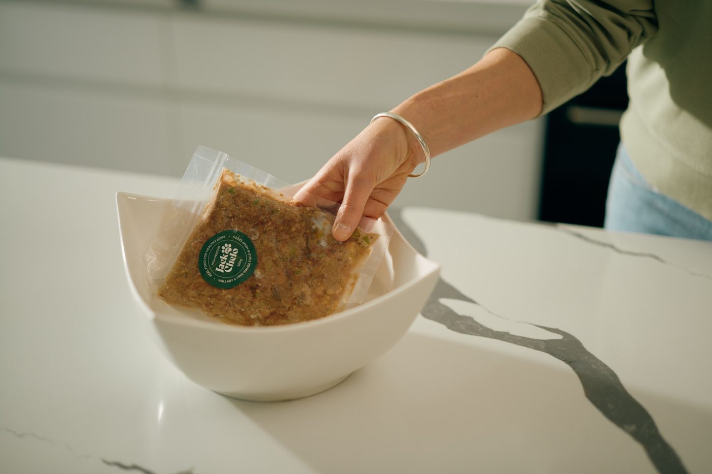 Placing a sealed Jack and Chelo meal in a bowl to defrost