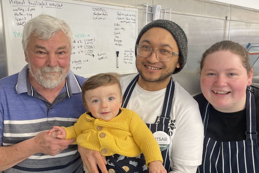 Members of the Jack and Chelo kitchen team, with a baby, in front of the week's prep board